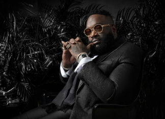 A confident man wearing a textured suit and gold sunglasses sitting thoughtfully, HD Desktop Wallpaper