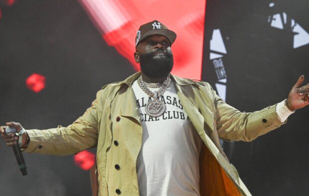 Rick Ross is performing live with a microphone on stage wearing a jacket and chains, HD Desktop Wallpaper