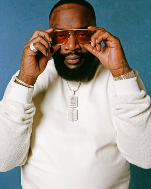 Rick Ross adjusting his sunglasses and wearing jewelry against a blue background, HD Mobile Wallpaper