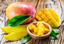 A ripe mango with sliced and cubed pieces displayed on a wooden surface, HD Desktop Wallpaper