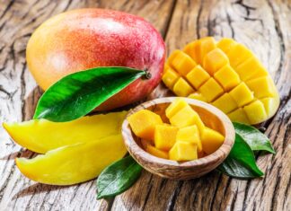 A ripe mango with sliced and cubed pieces displayed on a wooden surface, HD Desktop Wallpaper