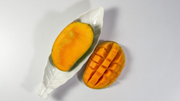 A ripe mango with cut pieces and a mango half on a white plate, HD Desktop Wallpaper