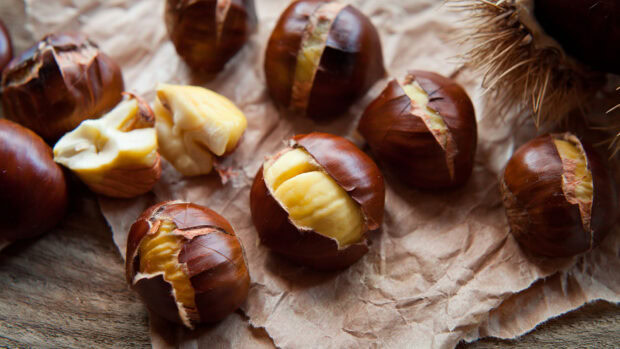 Roasted chestnuts are placed on a crumpled paper with some peeled shells visible, HD Desktop Wallpaper