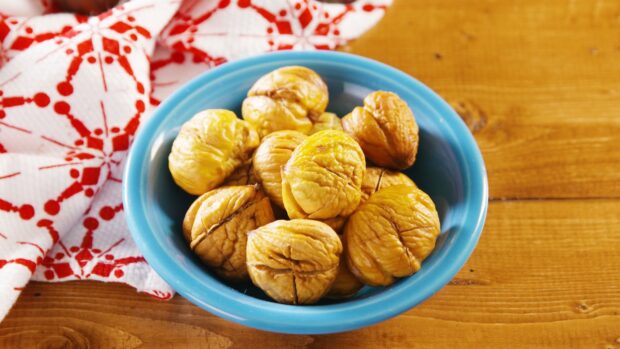 A bowl filled with roasted chestnuts on a wooden table with a red and white cloth, HD Desktop Wallpaper