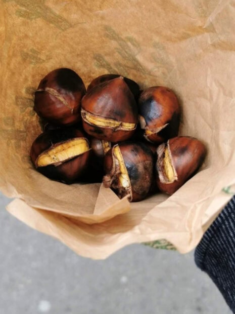 A bunch of roasted chestnuts placed inside a brown paper bag held by a person, 2K Phone Wallpaper