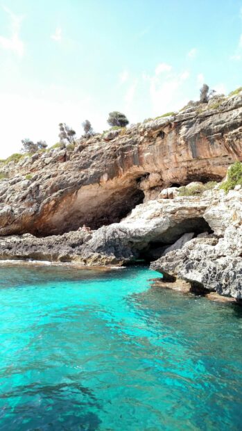A rocky coastline with bright turquoise water in Spain shows natural beauty and calm surroundings