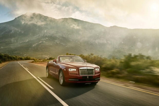 A Rolls Royce Dawn is driving along a winding mountain road under cloudy skies, HD Desktop Wallpaper