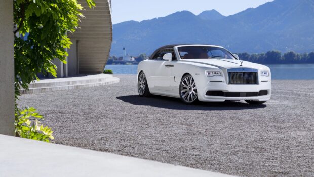 A white Rolls Royce Dawn convertible is parked near a modern building with mountains in the background, 4K Desktop Wallpaper
