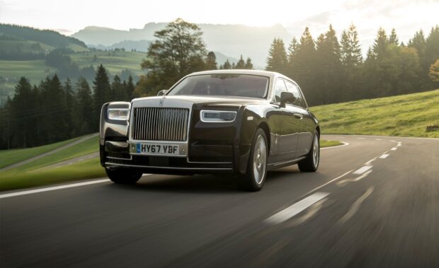 A Rolls Royce Phantom is driving along a winding road surrounded by trees and hills, HD Desktop Wallpaper