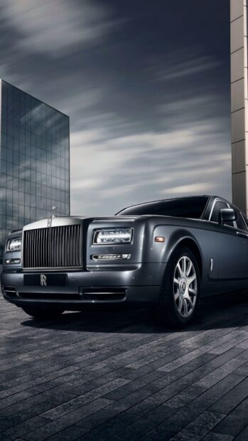 A sleek Rolls Royce Phantom is parked near a modern glass building under a cloudy sky, HD Phone Wallpaper