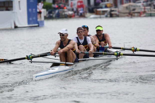 A team of rowers coordinating their rowing on a calm water surface in a rowing competition
