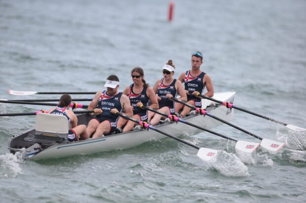 A team of rowers in uniform practicing rowing on a lake during a competition