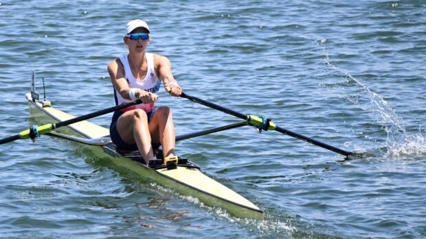 Female athlete rowing on calm water with a single scull boat in a competitive race