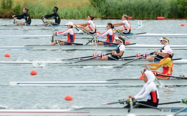Female athletes rowing during a competitive rowing race on calm water in multiple boats