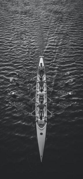 A rowing team practicing in a boat on calm water during training session