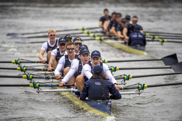 Male rowing team training together on a river during a competitive rowing event