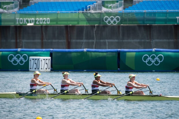 Female rowing team competing during Tokyo 2020 Olympic event on calm water