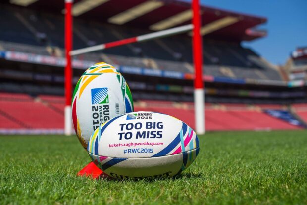 Two rugby league balls rest on green grass in a stadium, 2K Desktop Wallpaper