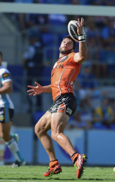 A rugby league player in an orange uniform is catching the ball during a match, HD Mobile Wallpaper
