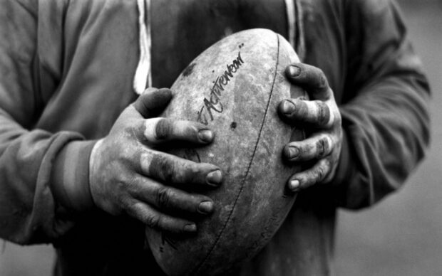 A rugby league player holds a worn ball with both hands preparing for the game, HD Desktop Wallpaper