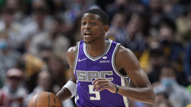 A Sacramento Kings player wearing a purple SAC jersey dribbles the basketball during a game