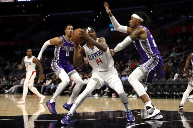 Sacramento Kings players defending against a Clippers player holding the basketball during an intense NBA game