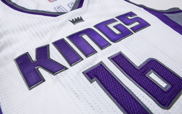 Close up of a Sacramento Kings basketball jersey with purple lettering and number 16 on white fabric