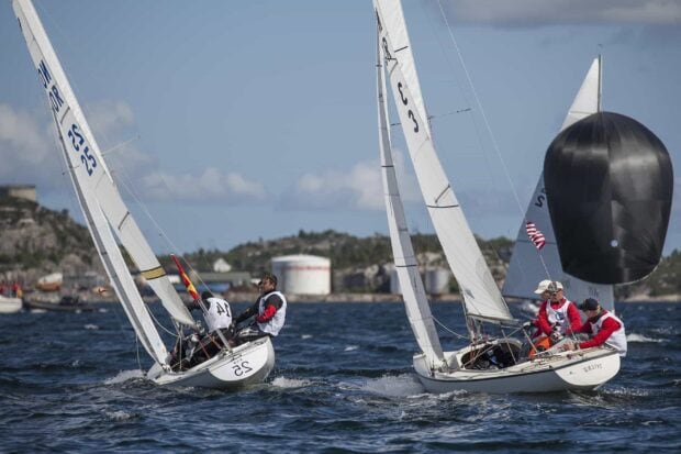 Two competing sailboats with crews navigating rough waters during a sailing race