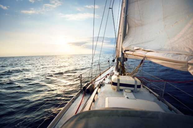 Calm ocean view from sailing boat deck at sunset with sailing rigging and ropes