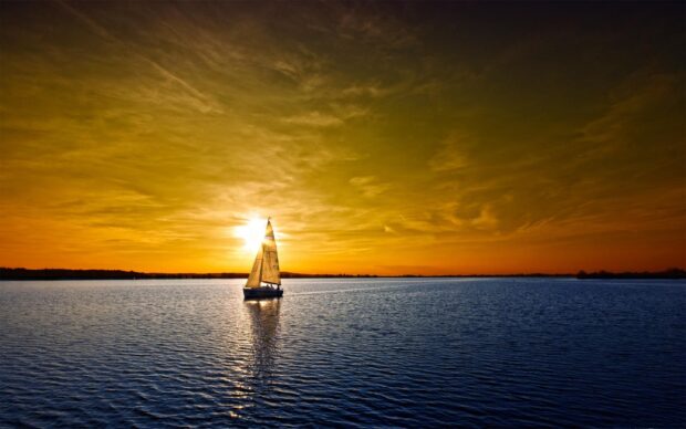 A sailing boat gliding across calm water during a sunset sailing