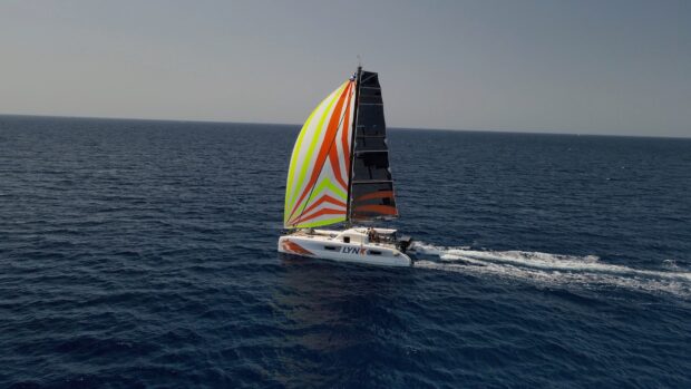 A sailing boat with colorful striped sails gliding on the deep blue ocean sea