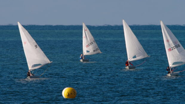 Four sailboats sailing on the calm sea during a race