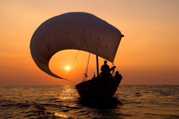 A sailing boat glides over lake Malawi during sunset with calm waters and orange sky, HD Desktop Wallpaper