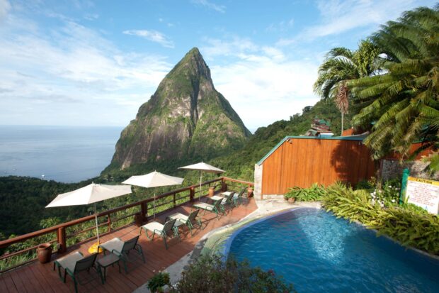 A stunning view of Saint Lucia mountain with a poolside terrace and lounge chairs under umbrellas