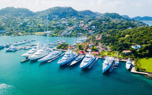 Luxury yachts docked in Saint Lucia harbor surrounded by lush green hills
