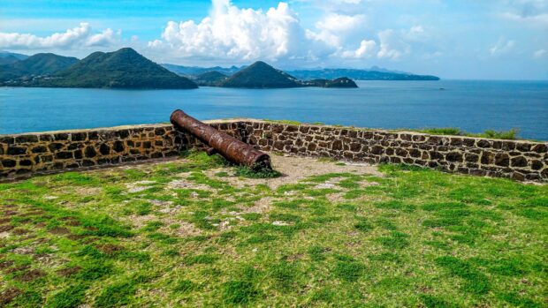 Rusty cannon on a historic stone wall overlooking Saint Lucia coastal landscape