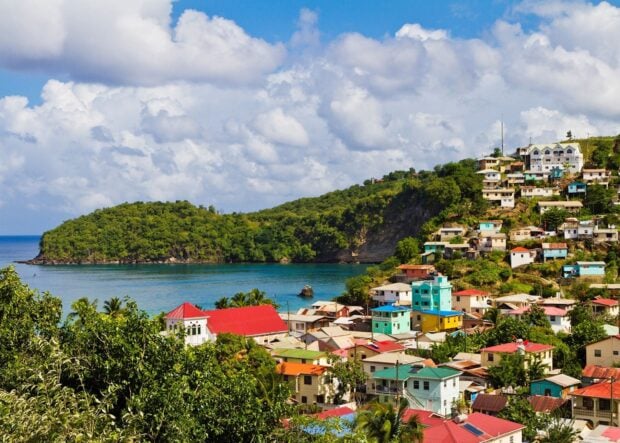 Colorful hillside village in Saint Lucia with lush greenery and calm blue water