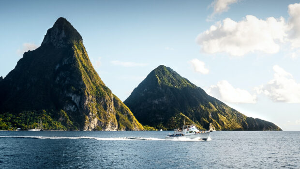 A boat sailing near the lush green mountains of Saint Lucia during a clear day