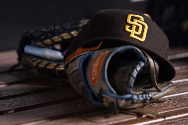 A San Diego Padres cap rests on a baseball glove lying on a wooden surface, 2K Desktop Wallpaper