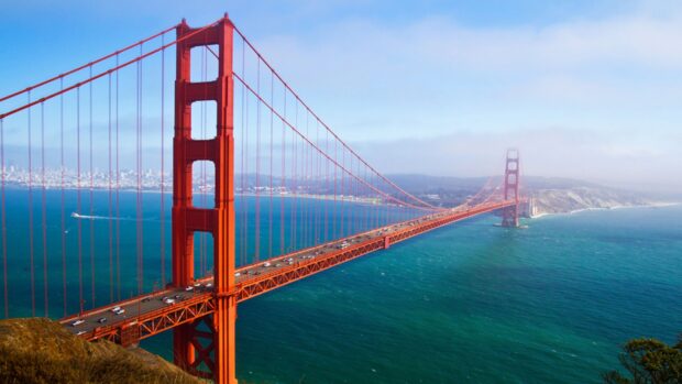 The San Francisco skyline with the iconic Golden Gate Bridge over blue water under a clear sky