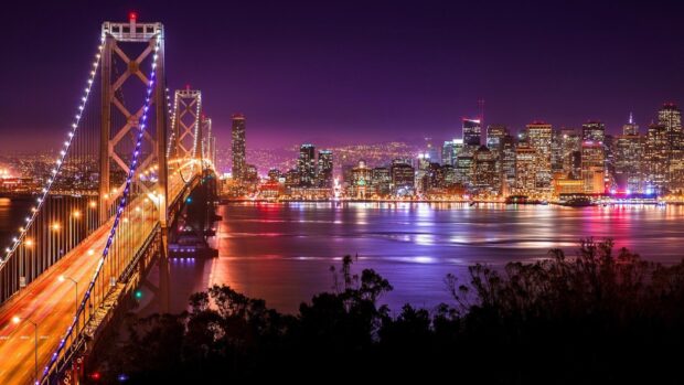 San Francisco skyline viewed at night with illuminated bridge and city lights reflecting on the water