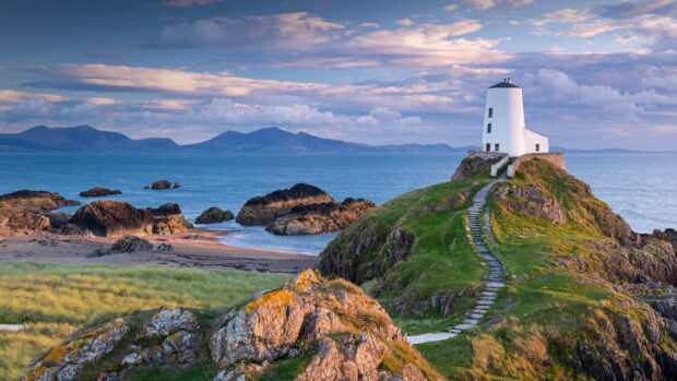 A white lighthouse stands on a rocky hill overlooking the sea in Wales Wallpapers, HD Desktop Wallpaper
