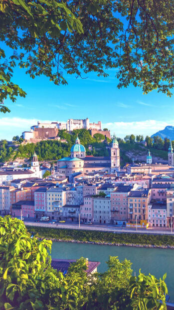 A scenic view of Austria cityscape with historic buildings and a river under a clear sky, HD Mobile Wallpaper