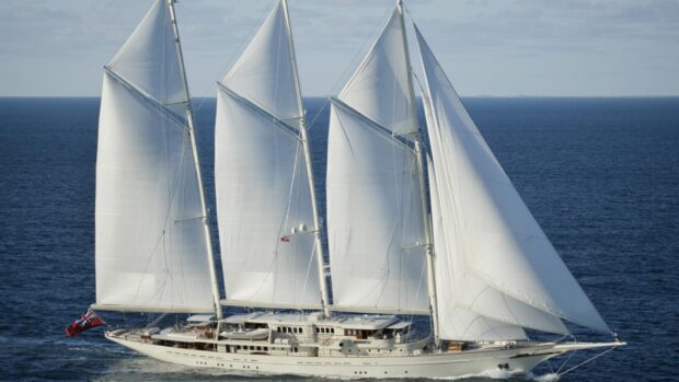 White schooner sailing on the calm blue sea under a partly cloudy sky