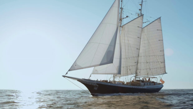A majestic schooner sailing on calm ocean waters under clear blue sky