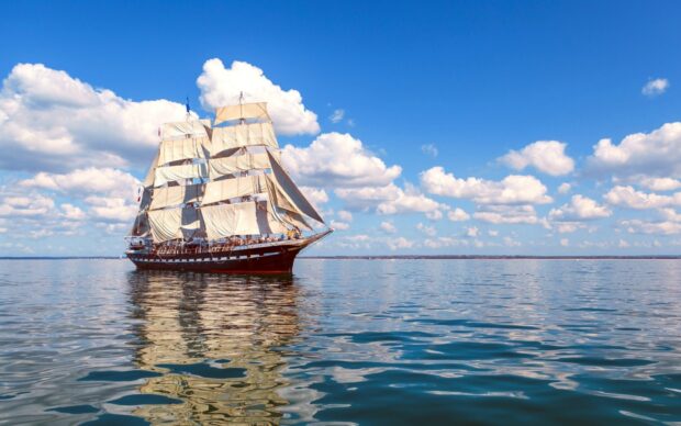 Large schooner sailing on calm sea under blue sky