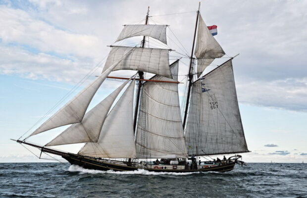 Old schooner sailing on the sea with full sails and a cloudy sky