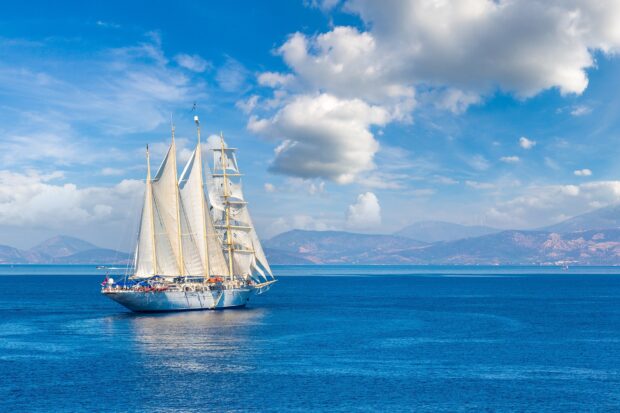 A majestic schooner sailing on blue ocean waters under a partly cloudy sky