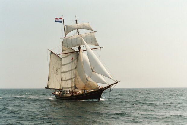 Classic schooner sailing on the open sea with full white sails and Dutch flag
