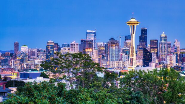 The Seattle skyline features the iconic Space Needle and illuminated buildings against a clear sky, 2K Desktop Wallpaper
